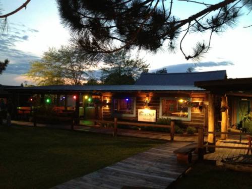 A rustic lodge with colorful lights at dusk, surrounded by trees and a wooden walkway.