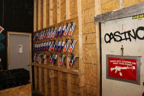 A wall displaying multiple toy guns, with a warning sign about magazine covers nearby.