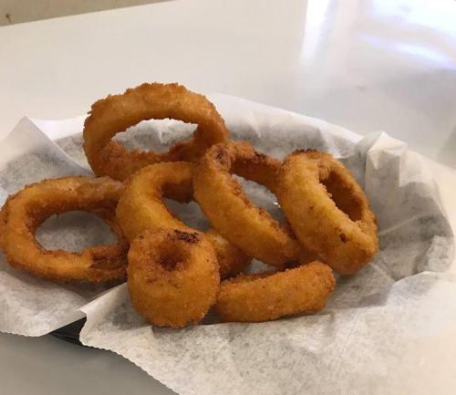 A plate of golden-brown onion rings arranged on a white paper liner.