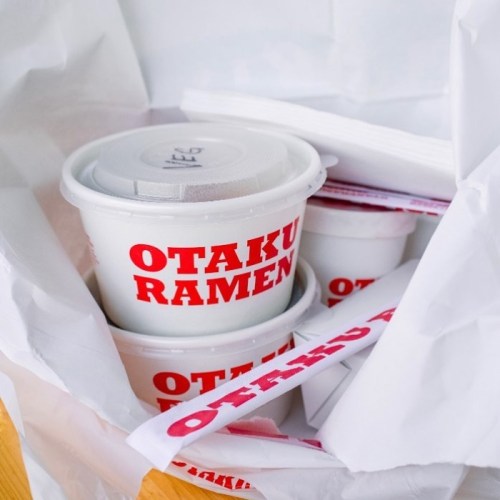 Takeout containers from Otaku Ramen, packed in a white bag with utensils and napkins.