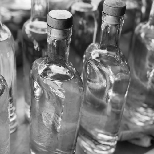 A close-up of several clear glass bottles with wooden corks, arranged in a blurred background.