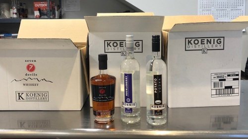 Three bottles of Koenig Distillery spirits, including whiskey and vodka, displayed with their packaging boxes.