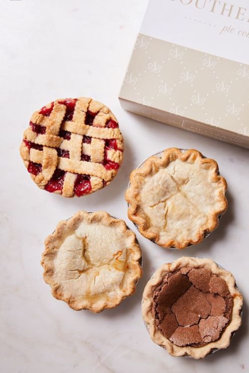 Four delicious pies on a marble surface, including a lattice-topped berry pie and three others with golden crusts.