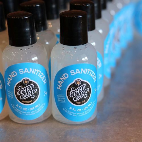 Bottles of hand sanitizer with blue labels, arranged neatly on a table.