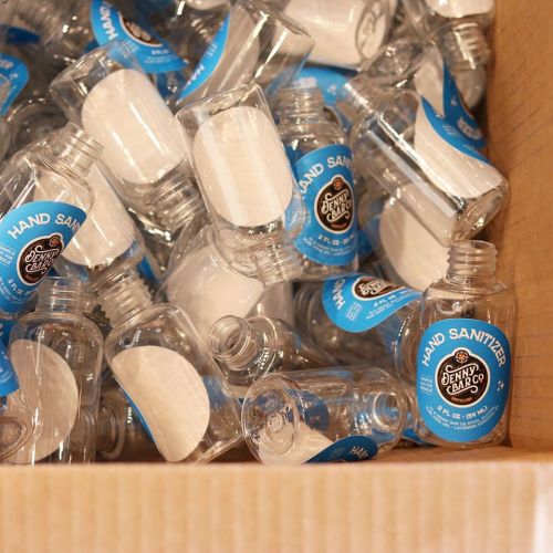 A box filled with clear hand sanitizer bottles, each labeled with a blue and black logo.
