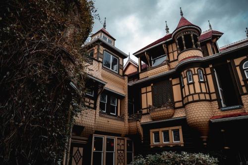 A unique, ornate building with a mix of architectural styles, featuring intricate details and a cloudy sky above.