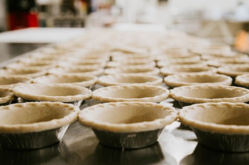 A row of empty pie crusts lined up on a kitchen counter, ready for filling.
