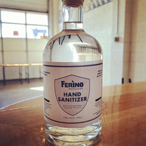 A clear bottle of Ferino Distillery hand sanitizer with a cork stopper, labeled 75% alcohol by volume.