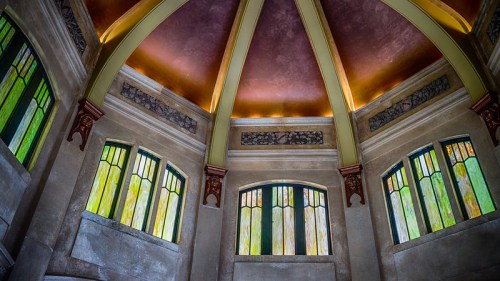 Interior view of a room with a domed ceiling, featuring stained glass windows and decorative architectural details.