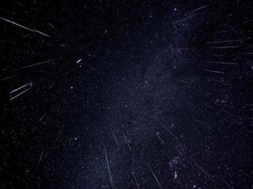 A starry night sky filled with streaks of light, resembling meteor showers against a dark backdrop.