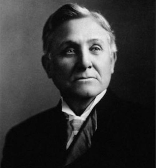 Black and white portrait of a distinguished older man in formal attire, looking thoughtfully to the side.