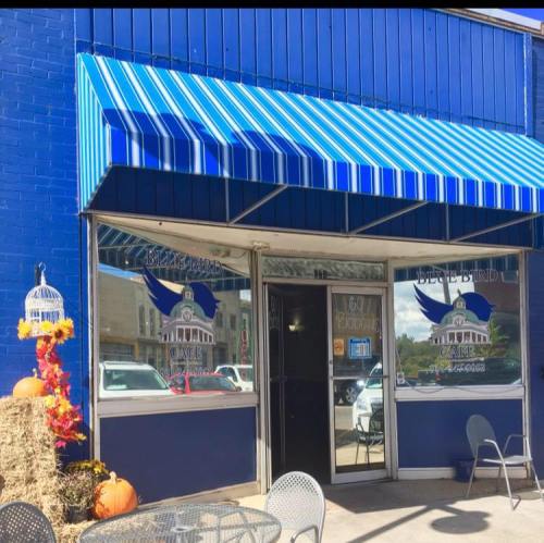 Exterior of Blue Bird Cafe with blue awning, decorative pumpkins, and a welcoming entrance.