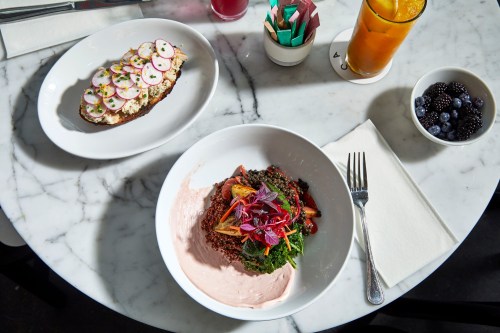 A marble table with a bowl of quinoa salad, a plate of toast with radishes, and a bowl of blackberries.