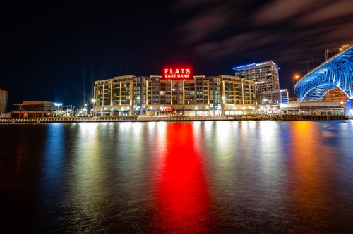 Night view of Flats East Bank with colorful reflections on the water and illuminated buildings along the waterfront.