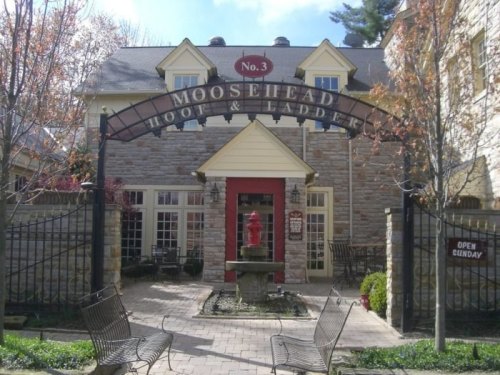 A charming stone building with a sign reading "Moosehead Hook & Ladder," featuring a fountain and outdoor seating.