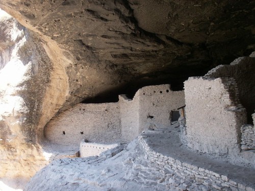 Ancient stone ruins inside a cave, with a rocky ceiling and remnants of walls and structures.