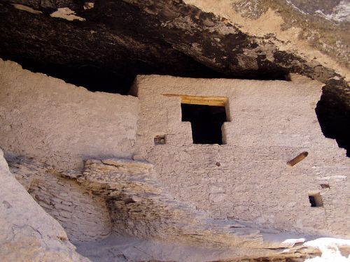 Ancient stone structure built into a cliff, featuring a window and steps leading up to it.