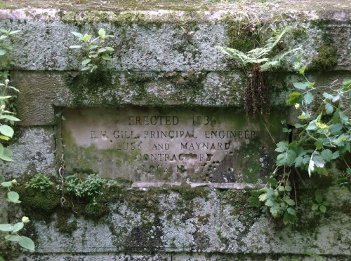 Stone plaque covered in moss and plants, inscribed with "Erected 1836" and names of engineers and contractors.