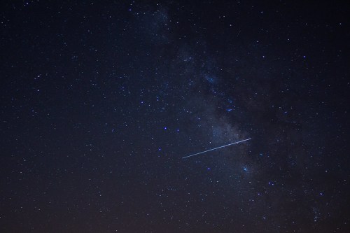 A starry night sky with the Milky Way and a bright meteor streaking across the scene.