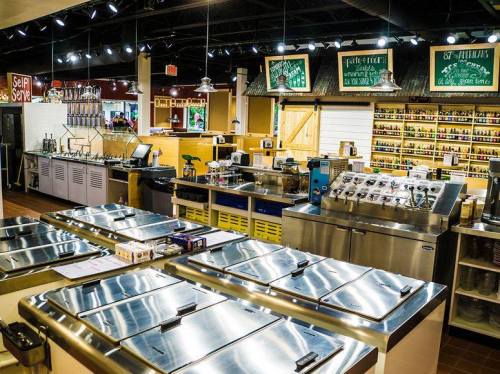 A spacious food service area with stainless steel counters, ice cream machines, and various toppings displayed on shelves.