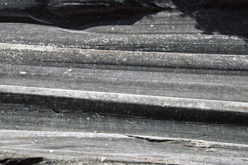 Close-up of textured, layered rock formations with varying shades of gray and subtle patterns.