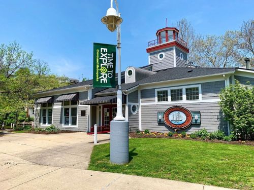A gray building with a lighthouse-style roof, featuring a "Time to Explore" banner and landscaped surroundings.