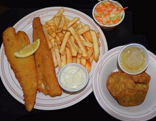 A plate of fried fish fillets with lemon, French fries, coleslaw, and hushpuppies, served with dipping sauces.