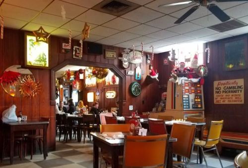 Cozy diner interior decorated for the holidays, featuring wooden walls, festive ornaments, and tables set for dining.