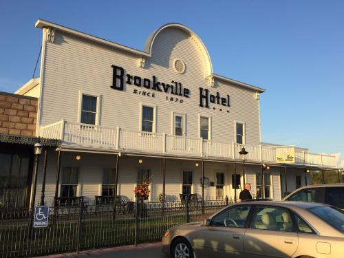 Historic Brookville Hotel building with a white facade, balconies, and a clear blue sky in the background.