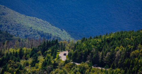 A winding road through lush green mountains under a clear blue sky.