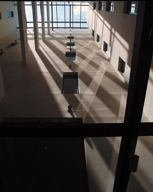 View looking up through a modern building's atrium, showcasing shadows and light from large windows above.