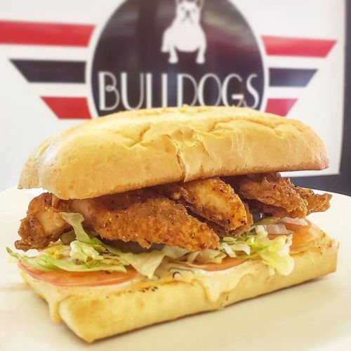 A delicious fried chicken sandwich with lettuce, tomato, and sauce on a toasted bun, served on a plate.