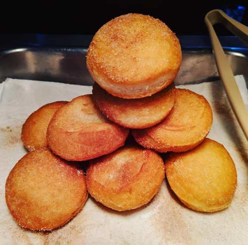 A pyramid of golden, sugar-coated doughnuts on a paper towel.