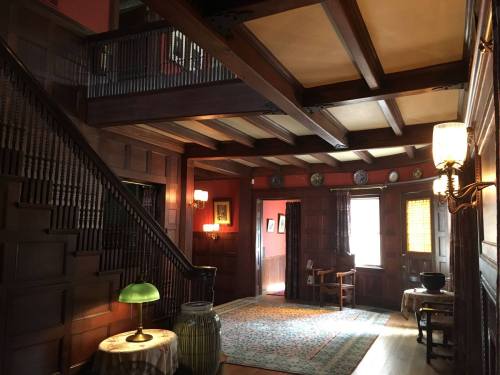 A cozy, wooden foyer with a staircase, vintage decor, and warm lighting, creating an inviting atmosphere.
