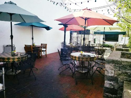 Outdoor dining area with tables and umbrellas, surrounded by greenery and string lights.
