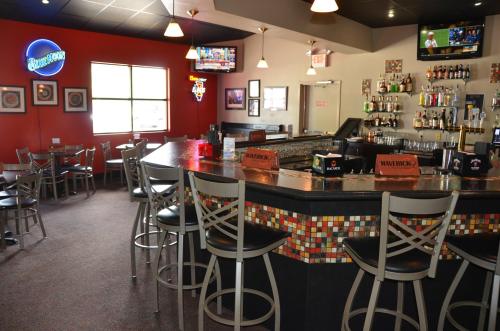 A cozy bar area with high stools, a colorful mosaic counter, and TVs displaying sports in a warm, inviting setting.