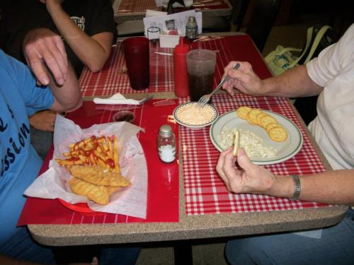 A table with two plates of food: one with fries and ketchup, the other with rice and crackers, alongside drinks.