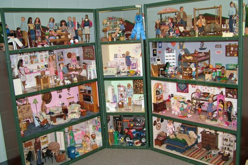 A colorful display of dollhouses with various rooms, furniture, and dolls arranged in a showcase.