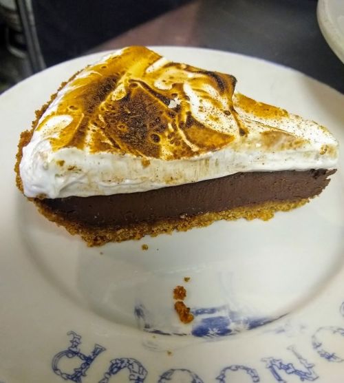 A slice of chocolate pie with a toasted meringue topping on a white plate.