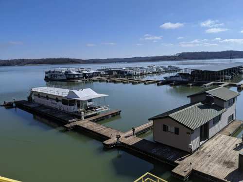 A serene lake view with houseboats and docks under a clear blue sky.