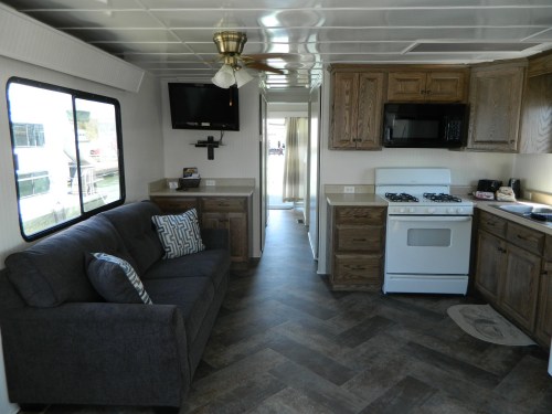 Interior of a cozy kitchen and living area in a houseboat, featuring a sofa, TV, and modern appliances.
