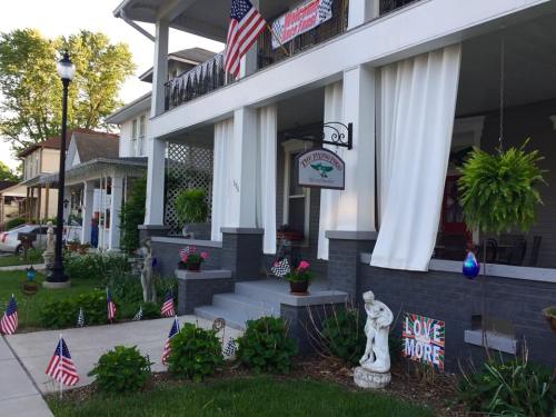 A charming house with American flags, potted plants, and a welcoming porch adorned with decorative signs.