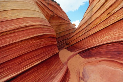 A winding sandstone canyon with vibrant red and orange stripes under a blue sky.