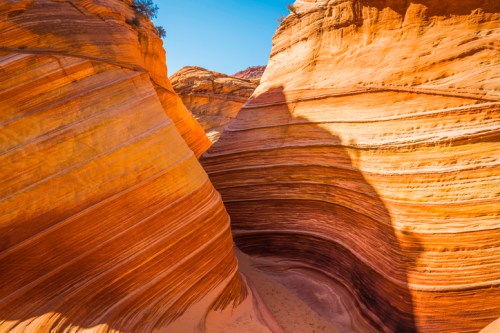 A stunning view of layered sandstone formations in a narrow canyon, illuminated by sunlight.