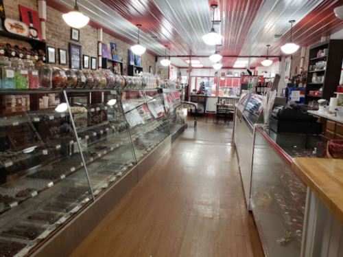 Interior of a candy shop featuring glass display cases filled with various sweets and a warm, inviting atmosphere.