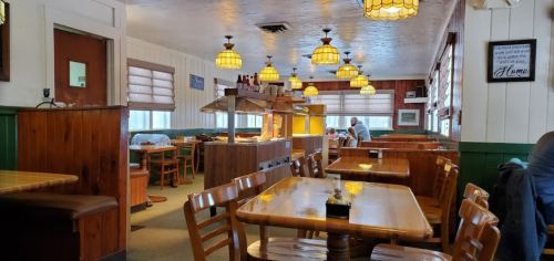 Cozy restaurant interior with wooden tables, pendant lights, and a buffet area, featuring a warm, inviting atmosphere.