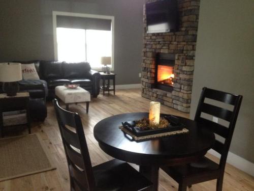 Cozy living room with a stone fireplace, black furniture, and a small dining table with a candle centerpiece.