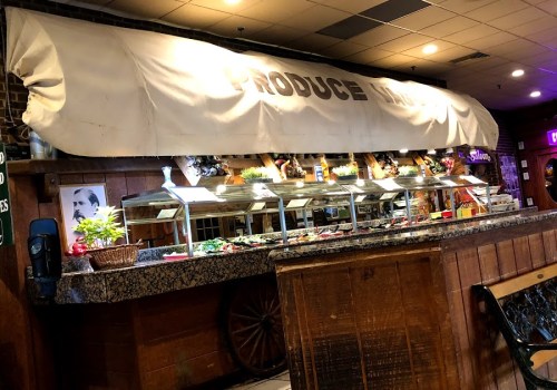A buffet table with a white canopy, featuring various food items and a rustic wooden backdrop in a restaurant setting.