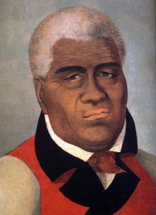 Portrait of a man with short white hair, wearing a red and black outfit, displaying a serious expression.
