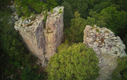Aerial view of tall, rugged rock formations surrounded by dense green trees.
